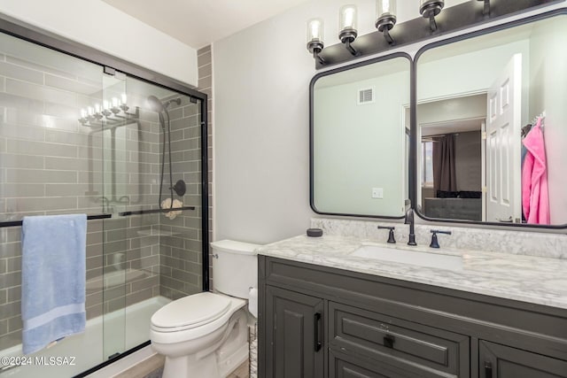 bathroom featuring vanity, toilet, and an enclosed shower