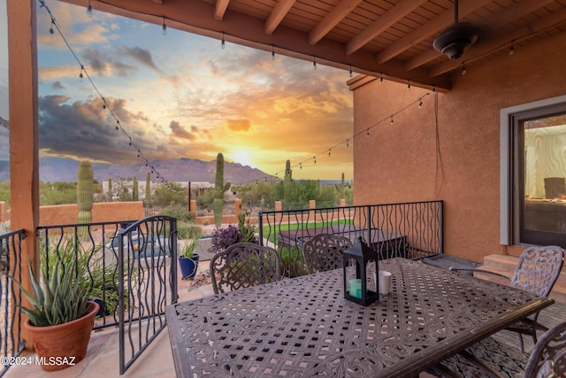 patio terrace at dusk featuring a mountain view and a balcony