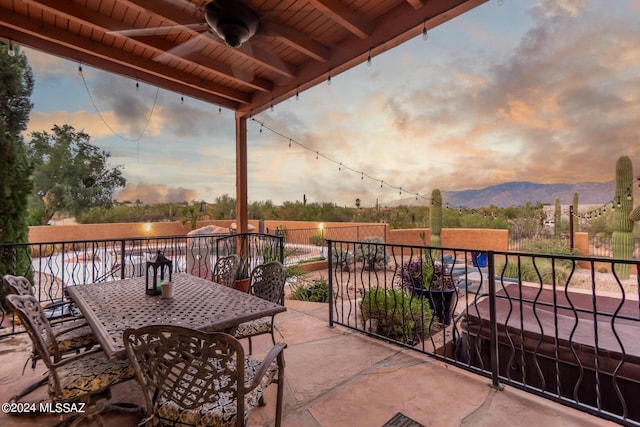 patio terrace at dusk featuring ceiling fan and a mountain view