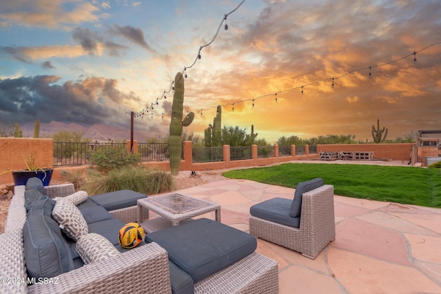 patio terrace at dusk with an outdoor living space and a yard