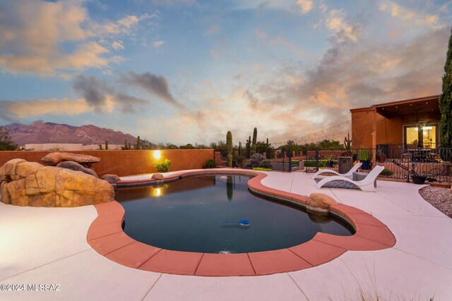 pool at dusk with a mountain view and a patio