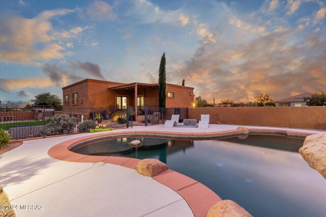 pool at dusk featuring a mountain view and a patio