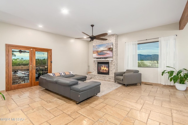 living room with a fireplace, french doors, and ceiling fan