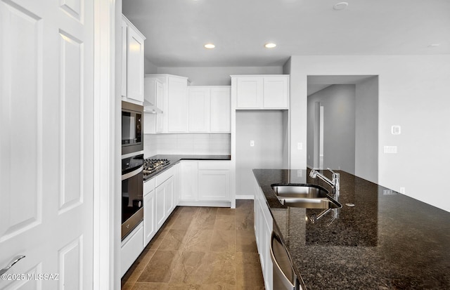 kitchen featuring dark stone countertops, stainless steel appliances, sink, and white cabinets