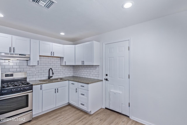 kitchen featuring gas stove, decorative backsplash, sink, light hardwood / wood-style flooring, and white cabinets