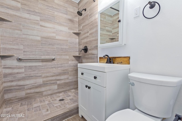 bathroom featuring toilet, vanity, and tiled shower