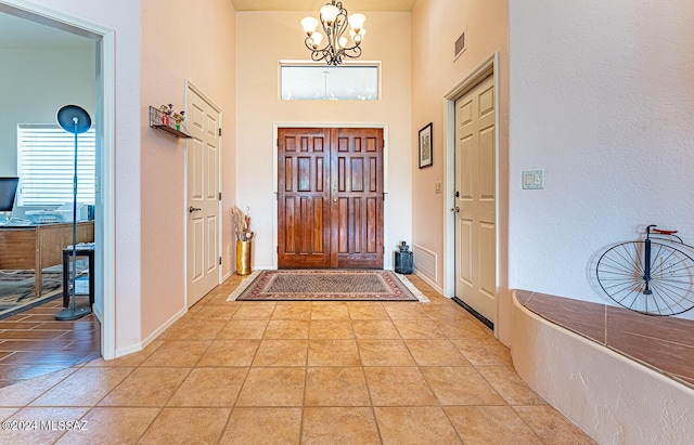 entryway with a high ceiling, light tile patterned floors, and a chandelier