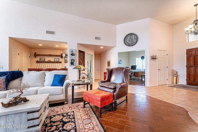 living room featuring a high ceiling, wood-type flooring, and an inviting chandelier