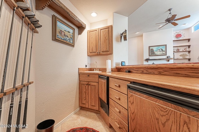 kitchen with butcher block counters, sink, light tile patterned floors, and ceiling fan