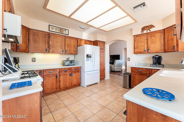 kitchen featuring light tile patterned floors, sink, and white fridge with ice dispenser