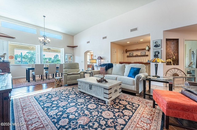 living room featuring a towering ceiling, wood-type flooring, and a chandelier