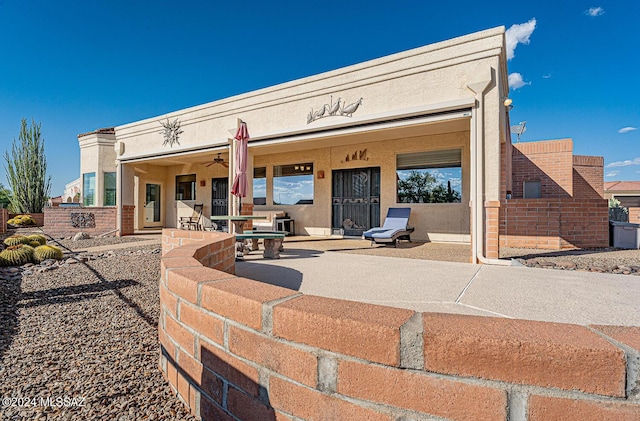 rear view of property with ceiling fan and a patio area