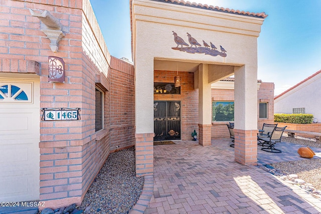 view of exterior entry with a garage and a patio area