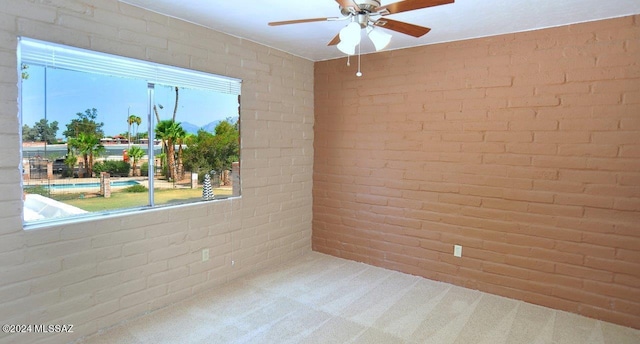 carpeted spare room featuring brick wall