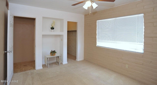 unfurnished bedroom with ceiling fan, brick wall, and light carpet