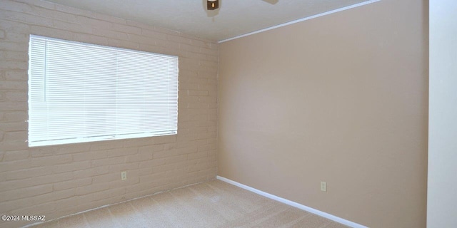 empty room featuring light colored carpet and brick wall