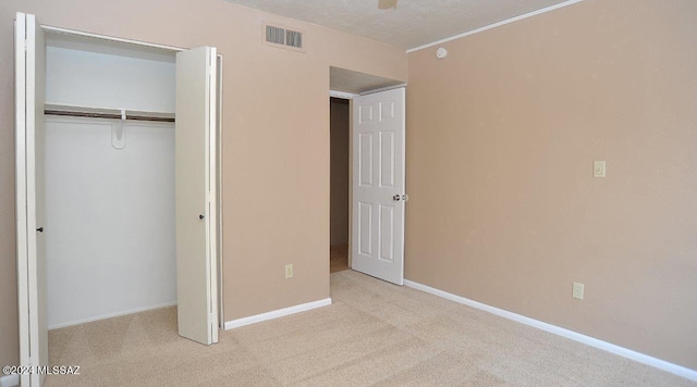 unfurnished bedroom featuring a textured ceiling, light carpet, and a closet