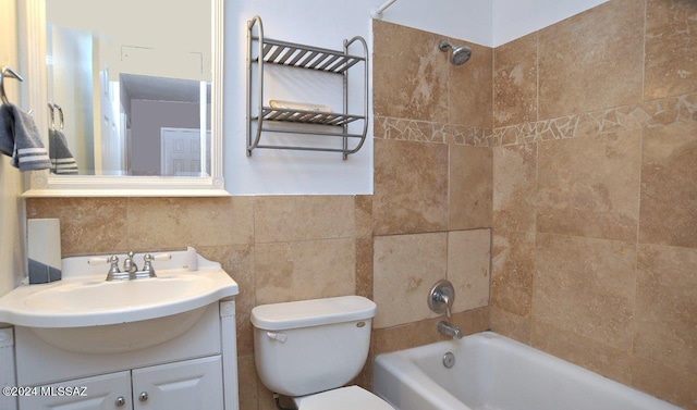 full bathroom with tiled shower / bath combo, tasteful backsplash, toilet, vanity, and tile walls