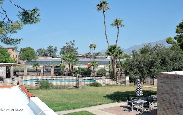 view of swimming pool with a mountain view, a patio area, and a yard