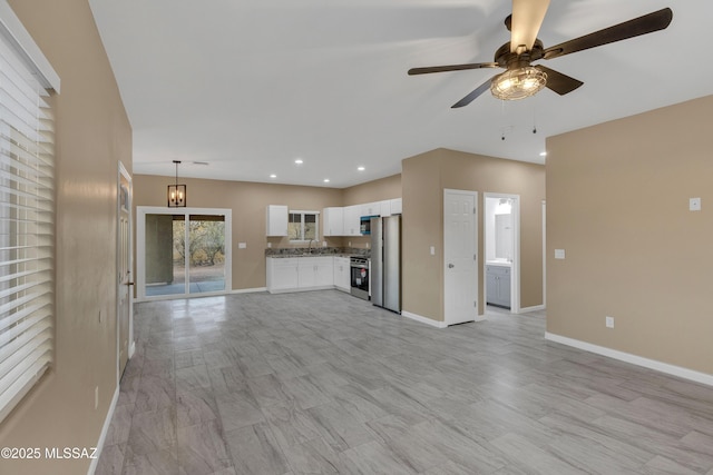 unfurnished living room with ceiling fan with notable chandelier and sink