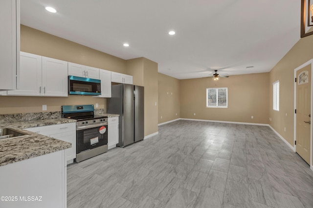 kitchen with light stone countertops, white cabinetry, ceiling fan, and stainless steel appliances