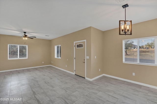 empty room with ceiling fan with notable chandelier and a wealth of natural light