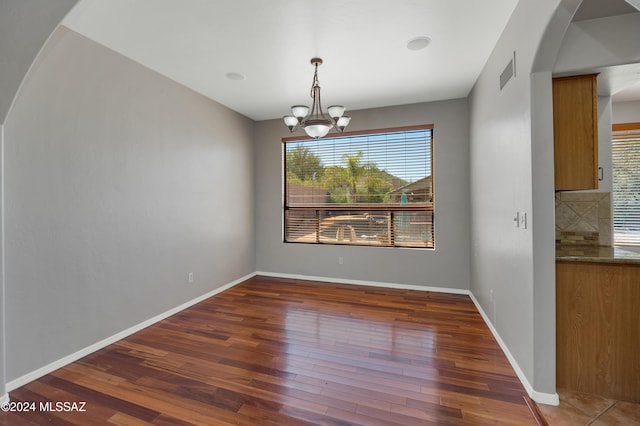 unfurnished dining area with a notable chandelier and dark hardwood / wood-style flooring