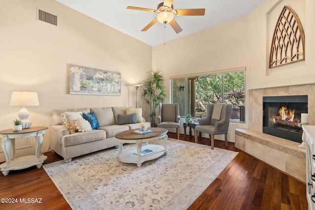 living room featuring dark hardwood / wood-style flooring, a high ceiling, ceiling fan, and a fireplace