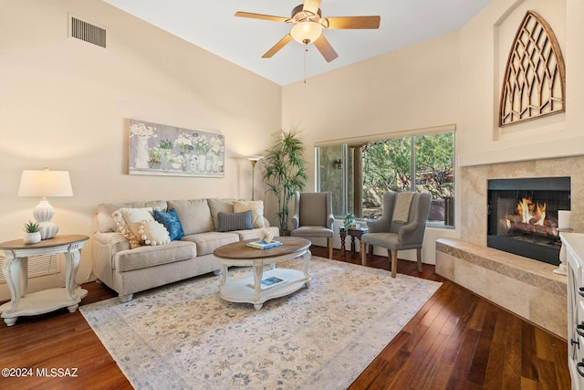 living area featuring a fireplace, dark wood-type flooring, a ceiling fan, and visible vents
