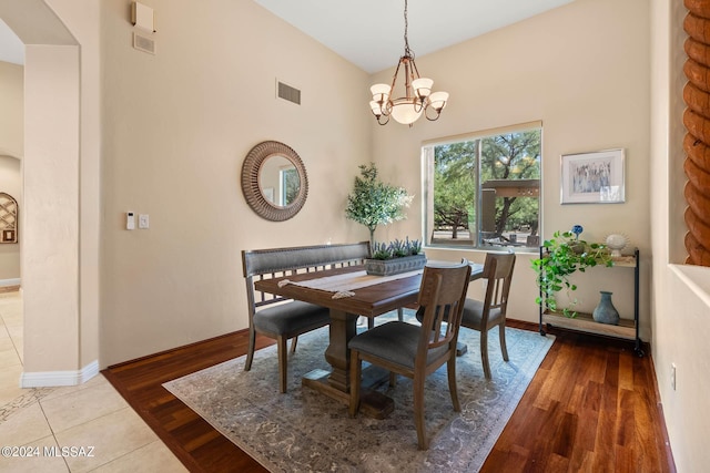 dining space featuring arched walkways, visible vents, an inviting chandelier, and wood finished floors