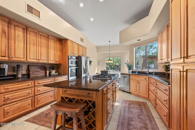 kitchen with stainless steel appliances, a kitchen island, dark stone countertops, pendant lighting, and light tile patterned floors