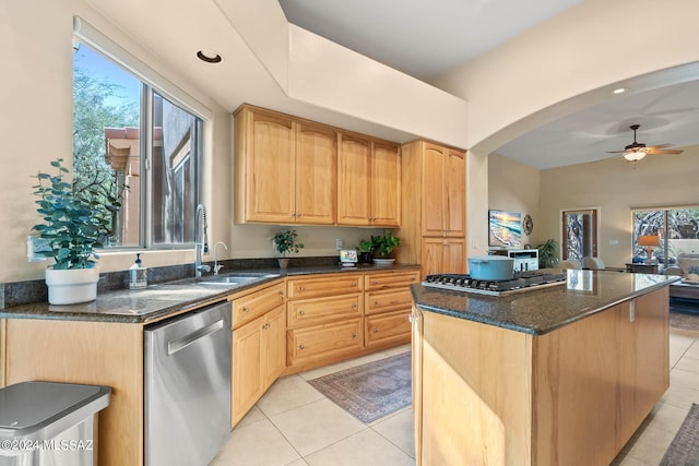 kitchen featuring appliances with stainless steel finishes, light tile patterned floors, a center island, and dark stone counters