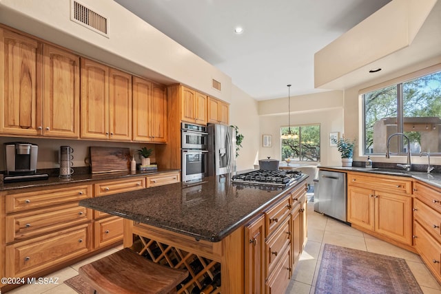 kitchen with visible vents, dark stone countertops, stainless steel appliances, and a sink