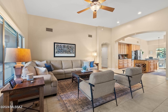 living area with light tile patterned flooring, visible vents, arched walkways, and ceiling fan