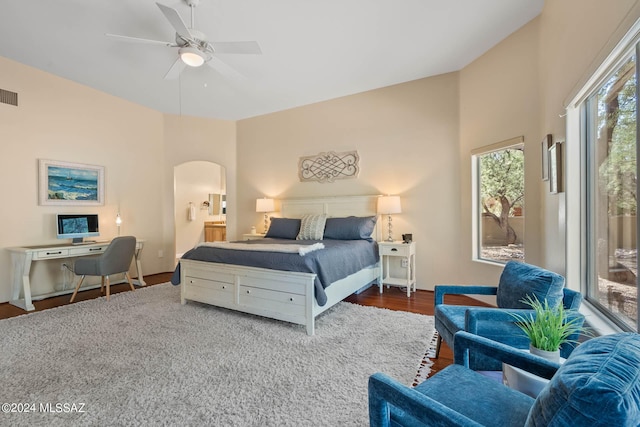 bedroom featuring visible vents, wood finished floors, connected bathroom, arched walkways, and access to exterior