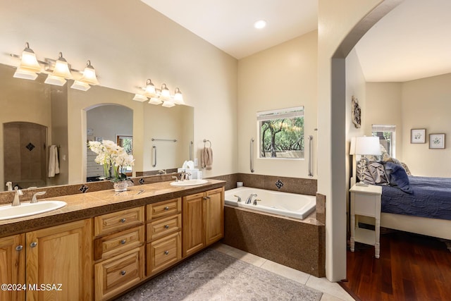 bathroom with tile patterned floors, vanity, and a relaxing tiled tub