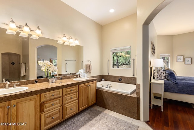 ensuite bathroom featuring a sink, connected bathroom, a garden tub, and double vanity