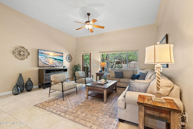 living area featuring baseboards, a high ceiling, light tile patterned flooring, and a ceiling fan