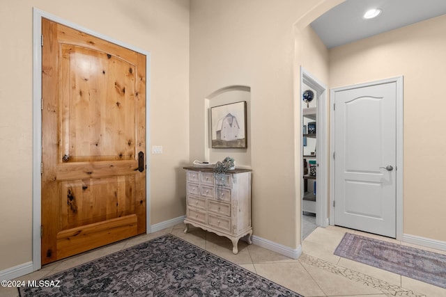 entryway featuring light tile patterned flooring, recessed lighting, baseboards, and arched walkways