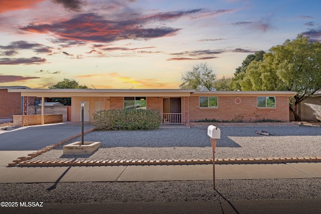 view of front of home featuring a carport, concrete driveway, and brick siding