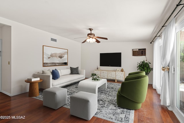 living area featuring a wall mounted AC, wood finished floors, visible vents, and ceiling fan