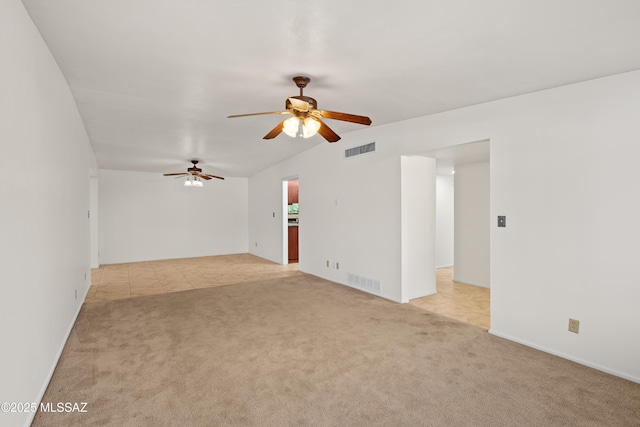 spare room featuring light tile patterned flooring, light colored carpet, visible vents, and ceiling fan