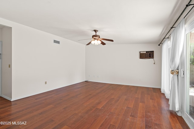 empty room with visible vents, dark wood-type flooring, baseboards, ceiling fan, and a wall mounted air conditioner