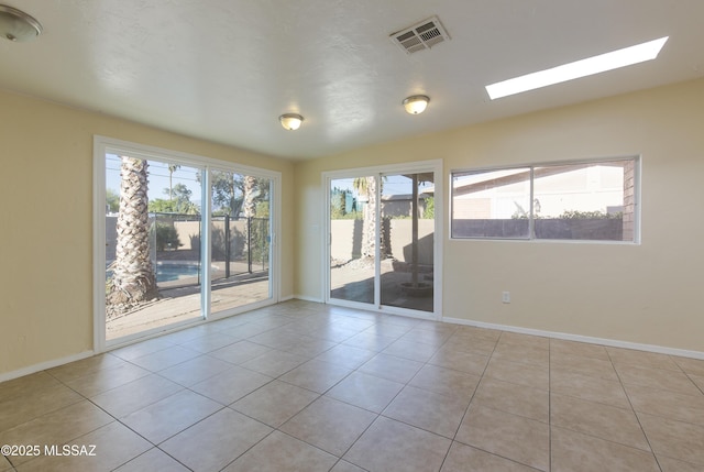 tiled spare room featuring vaulted ceiling with skylight