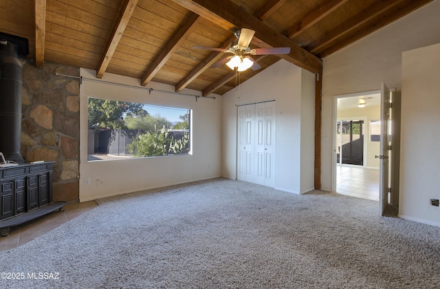 unfurnished living room with beamed ceiling, plenty of natural light, wooden ceiling, and a wood stove