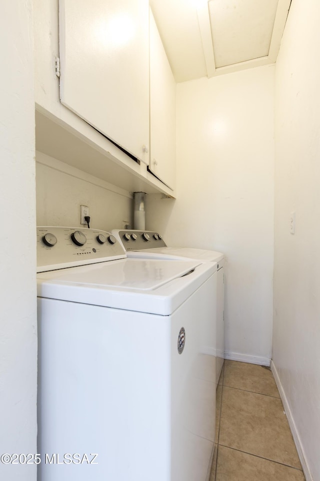 clothes washing area featuring cabinets, independent washer and dryer, and light tile patterned floors