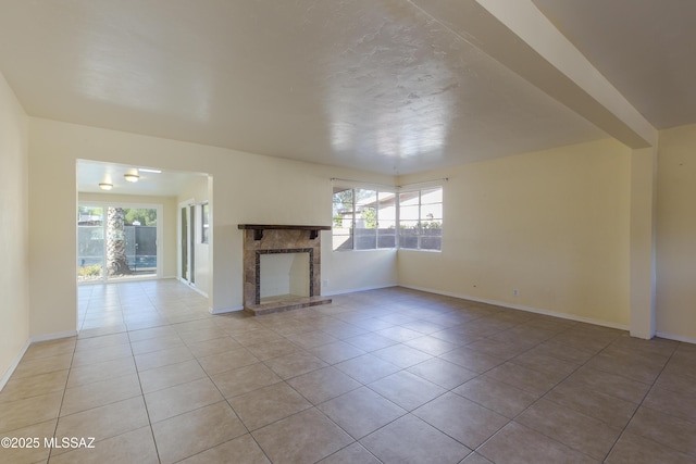 unfurnished living room featuring light tile patterned floors, a stone fireplace, and plenty of natural light