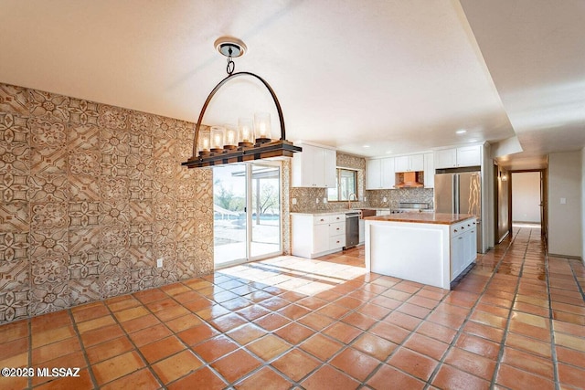 kitchen featuring a kitchen island, pendant lighting, decorative backsplash, stainless steel appliances, and white cabinets