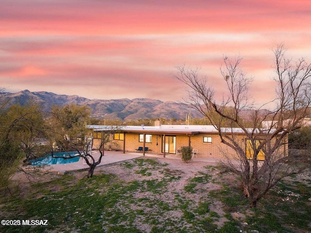 back house at dusk featuring a patio area and a mountain view