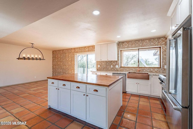 kitchen with a center island, pendant lighting, sink, white cabinetry, and stainless steel appliances